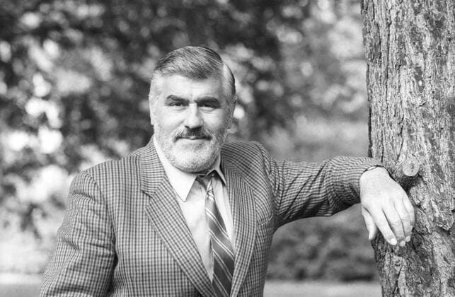 Mario Adorf (Schauspieler) 05 87 - Mario Adorf im Mai 1987 Deutschland deutsch Deutscher Mann Schauspiel Film Fernsehen TV Theater German actor quer halb Portrait stehend lächelnd draußen angelehnt anlehnend Baum Baumstamm sw