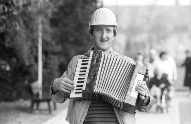 Mike Krüger (Komiker) 09 83 ru Mike Krüger am 29.09.1983 in Salzkotten Deutschland deutscher Deutscher Mann Comedian Kabarettist Musiker Musik Schauspieler Moderator Gesang TV Fernsehen Unterhaltungssendung Comedy german singer actor quer halb leger Bauhelm Helm Kopfbedeckung lächelnd musizierend Musikinstrument Instrument Akkordeon Baum Bäume draußen Personen Fans sw