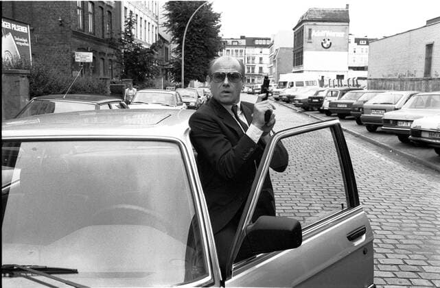Klaus Löwitsch in Peter Strohm (ARD) 09 87 dar Klaus Löwitsch,im September 1987 in Peter Strohm (ARD) TV-Produktion Fernsehen Serie Fernsehserie Fernsehreihe Reihe Deutschland deutsch Deutscher Mann Schauspieler Schauspiel Film TV Fernsehen Auto Fahrzeug Kfz offene Tür Sonnenbrille Halbglatze Anzug Pistole Waffe haltend Querformat quer halb stehend Außenaufnahme draußen Szene Szenenfoto sw