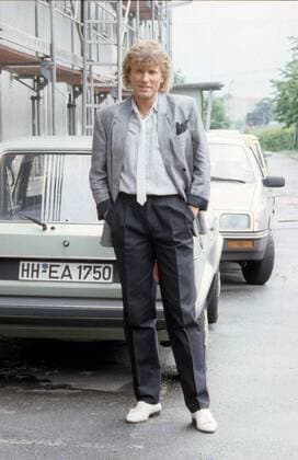 Bernhard Brink (Sänger) 06 84 vZ Bernhard Brink im Juni 1984 am Rande einer Aufzeichnung von Glücksspirale Deutschland deutsch Deutscher Mann Musik Musiker Schlagersänger Schlager Gesang Moderator Moderation german presenter singer blond kurzhaarig lockig leger Jackett Hemd Lederkrawatte Einstecktuch Bundfalte Auto Golf VW hoch ganz freistellbar stehend lächelnd draußen