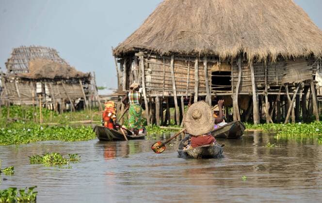 (111208) -- ABIDJAN, Dec. 8, 2011 (Xinhua) -- Photo taken on Dec. 7, 2011 shows villagers of the Ganvie water village travel by boat near Cotonou, economic capital of Benin. nicknamed Venice in Africa and with a history of more than 300 years, the Ganvie water village on the Nocue lake in Cotonou is a water residential area that has been well-preserved in Africa. (Xinhua Zhao Yingquan) BENIN-COTONOU-WATER VILLAGE 