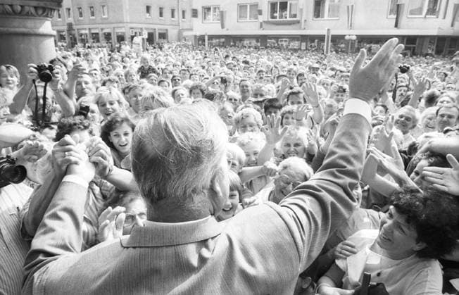Dr. Helmut Kohl (Bundeskanzler) 07 86 rag Dr. Helmut Kohl zu Besuch beim Libori-Fest in Paderborn im Juli 1986 Volksfest Kirmes Liborius Paderborner Stadt Innenstadt City Fußgängerzone Passanten Deutschland deutsch Deutscher Mann Politik CDU Politiker Kanzler german Germany Federal Chancellor Politician quer halb draußen gestikulierend winkend Rücken Rückansicht Menschenmasse Menschenmenge sw