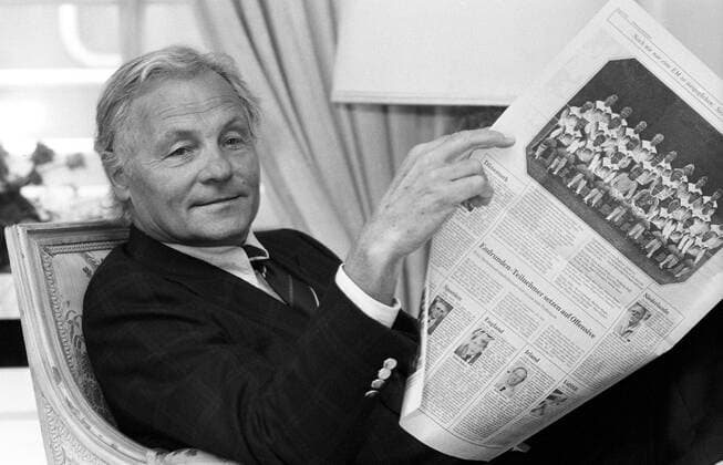 Harry Valerien (Sportjournalist) 06 88 hof Harry Valerien im Juni 1988 während der Fußball-Europameisterschaft 1988 Uefa Europameisterschaft Fußballspiel Länderspiel Nationalspiel Qualifikation Deutschland deutsch Deutscher Mann Sport Fußball Journalist Journalismus Moderator Moderation Autor Sportmoderator grauhaarig kurzhaarig seriös Jackett Sakko Krawatte Hemd quer Portrait halb sitzend Sessel Stuhl Zeitung lesend lesen Mannschaft Mannschaftsfoto Fußballmannschaft sw