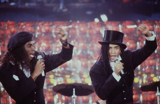 Milli Vanilli (Popduo, Fab & Rob) 01 89 dar Männer Mann Musiker Musik Gesang Sänger Gruppe Band Duo dunkelhäutig dunkelhaarig langhaarig Zöpfe Rastazöpfe Rastafrisur Rasta Mütze Zylinder seriös Jackett schwarz Hemd weiß stehend Saal Halle Bühne Auftritt Konzert live halb quer singend gestikulierend Mikrophon haltend links: Fabrice Morvan rechts: Robert Pilatus