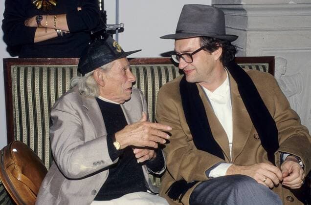 Wim Wenders, 75. Geburtstag am 14. August Wim Wenders mit Samuel Fuller (li.) 11 93 kück Mann Fernsehen Film Regie dunkelhaarig Brille seriös quer halb sitzend Hut Mantel Gespräch unterhaltend