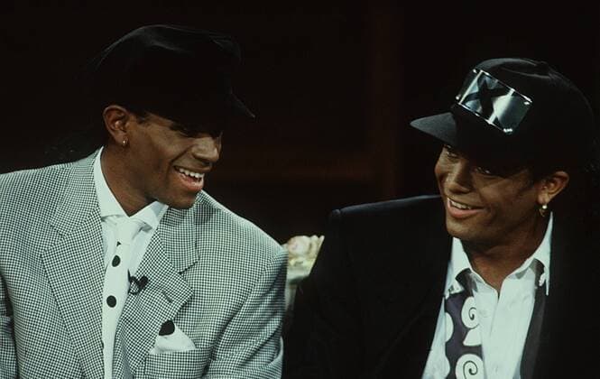 Milli Vanilli Fabrice Morvan (li.) und Robert Pilatus (re.) 11 91 te Musik Gesang Gruppe Pop Duo halb quer Studio sitzend leger Mütze Käppi Talkshow