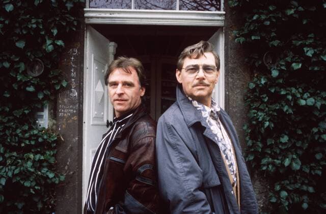 Oppen und Ehrlich (ARD) mit Uwe Friedrichsen (re.) und Andreas Schmidt-Schaller 12 90 ru TV Fernsehen Schauspiel Produktion Mann leger stehend draußen Haus Gebäude Außenansicht Tür angelehnt Portrait quer