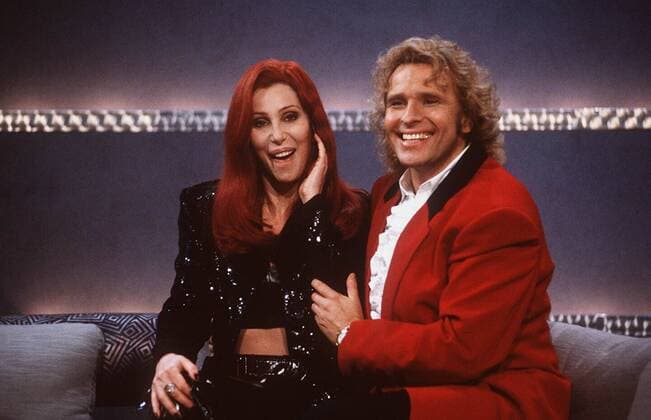 Wetten, daß...? (ZDF) Cher und Thomas Gottschalk 12 95 her Fernsehen TV Show 09.12.95 in Rostock festlich quer halb sitzend Sofa Studio lächelnd