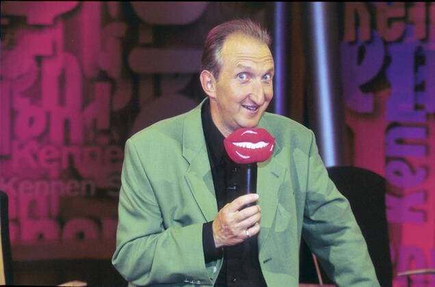 Mike Krüger in Kennen Sie den? (RTL) 06 97 rs Mann TV Schauspiel Show Moderation Film Kino Komik KABARETT dunkelhaarig Halbglatze leger Hemd schwarz Jackett stehend Studio Dekoration Kulisse Mikrophon haltend halb quer neutral