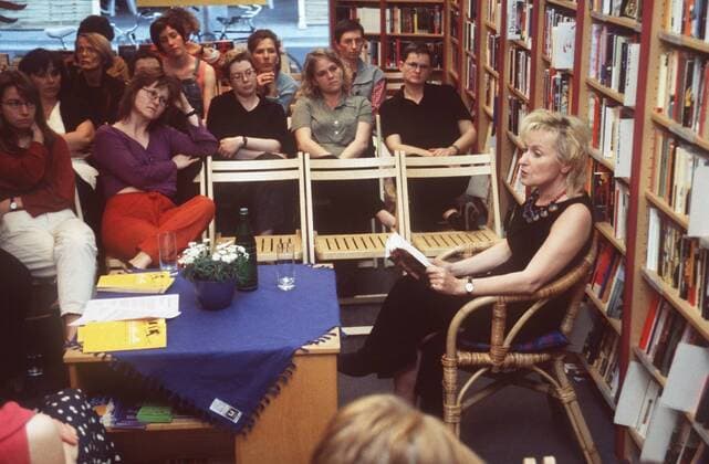 Bascha Mika (Journalistin, Autorin) 05 98 af Frau Journalismus Zeitung Zeitschrift Autor Literatur Schriftstellerei Buch blond LEGER Kleid schwarz Schmuck Kette sitzend Sessel Bücherregal Regal halb quer Buch haltend lesend Menschen Publikum