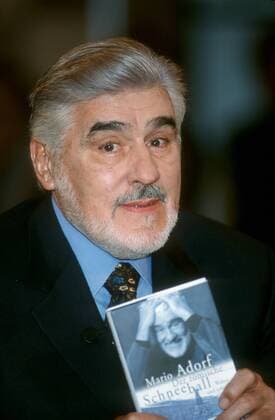Mario Adorf (Schauspieler) 02 00 her Mann Schauspiel Fernsehen TV Film Kino Serie grauhaarig kurzhaarig Bart Vollbart Schnäuzer seriös Jackett blau Hemd Krawatte sitzend Saal Halle dunkel Studio Show Talkshow halb hoch lächelnd interessiert eindringlich Buch haltend von ihm selbst Der römische Schneeball Wahre und erfundene Geschichten sein Foto Bild auf dem Cover Einband zeigend präsentierend hochhaltend NDR Talk Show (NDR) am 18.02.2000 in Hamburg
