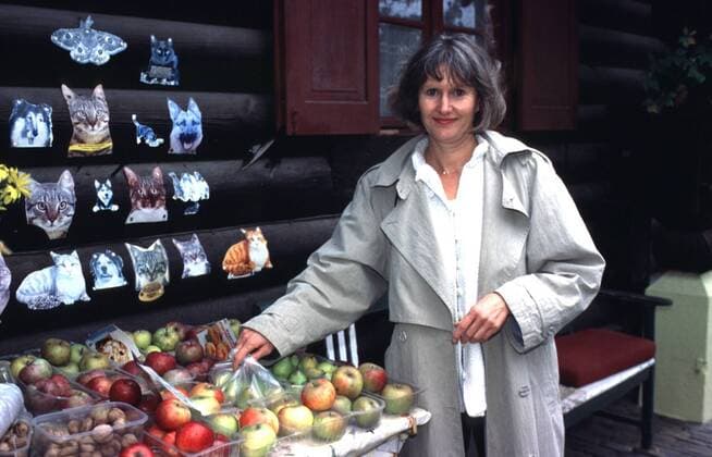 Claudia Loerding (Schauspielerin) 10 99 te Frau Schauspiel TV Fernsehen Serie RTL Der Frauenknast Hinter Gittern dunkelhaarig langhaarig leger Pullover Mantel Kette Schmuck stehend draußen Haus Blockhaus Laden Hofladen Lebensmittel Obst Apfel greifend halb quer lächelnd Homestor