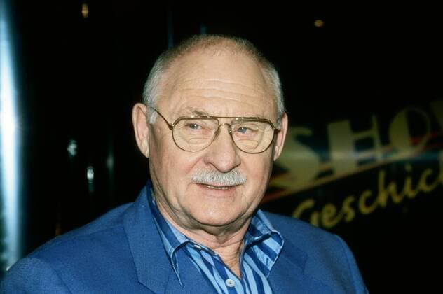 Rolf Schimpf (Schauspieler) 07 00 kück Mann Schauspiel TV Fernsehen Serie Krimi Der Alte Film grauhaarig kurzhaarig Stoppelschnitt Halbglatze Schnäuzer Brille leger Jackett blau Hemd blau gestreift sitzend Saal dunkel Studio Portrait quer lächelnd listig zur Seite schauend Fototermin Showgeschichten (ARD) am 12.07.2000 in München