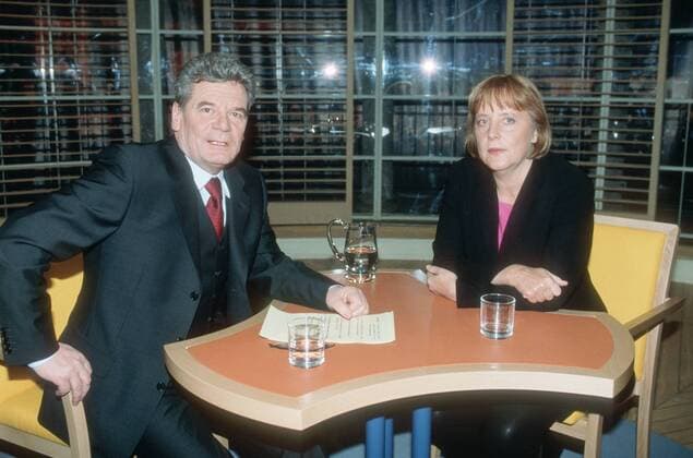 Joachim Gauck mit Angela Merkel in Joachim Gauck (ARD) 04 01 pp Mann Politik ehemaliger Bundesbeauftragter für die Unterlagen des Staatssicherheitsdienstes der ehemaligen DDR Behörde beauftragt vom Bund Staatssicherheitsdienst Staatssicherheit Ministerium Deutsche Demokratische Republik TV-Moderator Moderation TV Fernsehen Sendung Show Talkshow dunkelhaarig kurzhaarig sitzend Saal Studio Kulisse Dekoration halb quer Gespräch Tisch Unterlagen Glas Krug Getränk Wasser Fototermin Joachim Gauck (WDR ARD) am 18.04.2001 in Köln