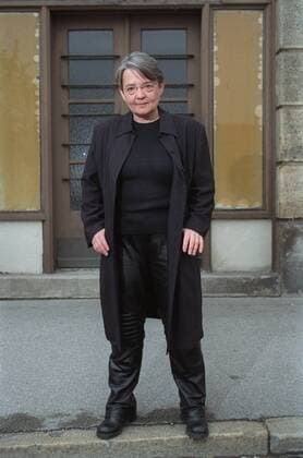 Agnieszka Holland (Regisseurin) 04 02 gra Frau geboren 1948 in Polen Polin Regie Film Hitlerjunge Salomon grauhaarig kurzhaarig Brille leger Mantel Shirt Hose Leder Lederhose stehend draussen vor Haus Gebäude Eingang ganz hoch lächelnd posierend Daumen in den Manteltaschen Fototermin Agnieszka Holland am 21.04.2002 im Filmmuseum in München (exklusiv) Foto: Nicolas Gradicsky