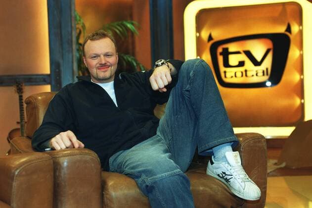 Stefan Raab in tv total (ProSieben) 01 03 pp Mann Moderator TV Fernsehen Moderation Musiker Musik Pop Gesang Sänger Produktion Unterhaltung Show dunkelhaarig kurzhaarig leger Trainingsjacke Sportjacke Shirt Jeans Turnschuhe sitzend TV-Studio Kulisse Dekoration Logo halb quer sitzend lächelnd angelehnt Sessel Fototermin tv total (ProSieben) am 06.01.2003 in Köln