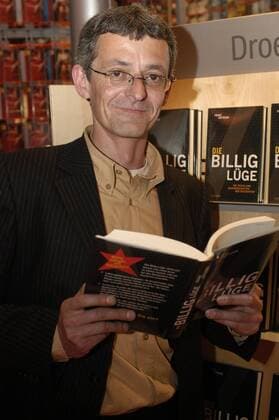 Franz Kotteder (Journalist) 10 05 pp Franz Kotteder am 21.10.2005 auf der Buchmesse 2005 in Frankfurt Main Mann Schriftsteller Autor Kultur politische Sachthemen Buch Die Billiglüge Bücher Messe Ausstellung Präsentation deutsch Deutscher Deutschland Anzug Hemd Brille kurzhaarig Regal Bücherregal hoch Hochformat halb