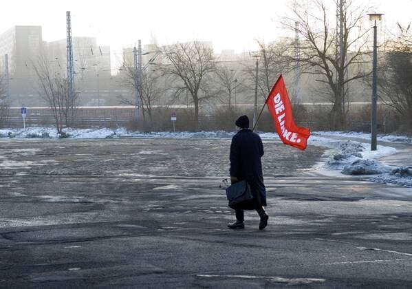 Die Linke, Luxemburg - Liebknecht - Gedenkveranstaltung DEU, Berlin, 15.01.2006 Teilnehmer auf der Gedenkstaette der Sozialisten in Berlin - Friedrichsfelde mit Fahne Die Linke der PDS, Die Linkspartei, Linkspartei.PDS anlaesslich der Luxemburg - Liebknecht - Gedenkveranstaltung. Der Gedenktag erinnert an die Ermordung der Kommunisten Rosa Luxemburg und Karl Liebknecht am 15. Januar 1919. Seit dem Ende der DDR hat die Veranstaltung eine neue Beliebtheit, hauptsaechlich unter Ostdeutschen, erfahren. Politik, Sozialismus, linke Gruppen, Ostdeutschland, ehemalige DDR, OstBerlin, Ost-Berlin, Links, Rot, Grau, Demonstation, Kundgebung, Deutschland, QF, Querformat. Demonstrant with flag Die Linke of the left wing party PDS Die Linkspartei at ralley in memory of the socialist leaders Rosa Luxemburg and Liebknecht at the graveyard in Friedrichsfelde in the former GDR. Eastgermany, East-Ger