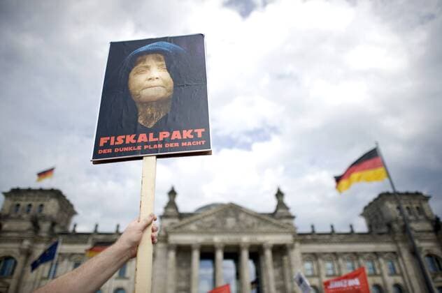 Protest Fiskalpakt DEU, Deutschland, Germany, Berlin, 29.06.2012 Demonstrant mit Plakat Fiskalpakt Der Dunkle Plan der Macht und Foto von Angela Merkel vor dem Reichstag in Berlin. Die Demonstrantion von attac, Der Linkspartei Die Linke, Die Piratenbpartei und anderen Gruppen wendet sich gegen den EU-Fiskalpakt und den Beschluessen zum ESM, Europaeische Stabilitaetsmechanismus. Im Plenarsaal Deutscher Bundestag tagt zeitgleich die Debatte zur Stabilitaetsunion, Fiskalvertrag, dem Euro-Rettungsfond EFSF und ESM, der Diskussion zu Eurobonds und dem Bruesseler Spargipfel. Parlament, Deutsche Politik, Bundespolitik, 2012, Symbol Symbolfoto, Symbolbild, Symbolisch, Finanzen, Euro-Krise, Rettungsfond, Finanzwirtschaft, Wirtschaft, Schulden, Sparen, Einsparen, EU Waehrung, Euro, europaeische, Europa, Feature, Haushaltspolitik, Staat, Staatsbudget, Staatsfinanzen, Fiskalpakt, Staatshaushalt, Fin