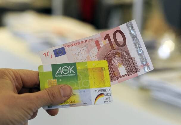 Die Praxisgebühr soll nach den Plänen der Koalition zum 1. Januar 2013 abgeschafft werden (Foto vom 09.11.12: Eine Frau hält ihre Gesundheitskarte mit einem 10-Euro Schein in der Hand). Der Bundestag stimmt darüber am Freitag (09.11.12) ab. Den Krankenkassen gehen damit pro Jahr rund zwei Milliarden Euro verloren. Dies soll durch zusätzliche Zuweisungen aus dem Gesundheitsfonds kompensiert werden. DER ABDRUCK DES EPD-FOTOS IST HONORARPFLICHTIG! Praxisgebühr soll abgeschafft werden 398816 EDITORIAL USE ONLY