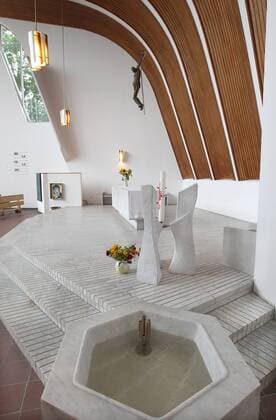 Architektur von Alvar Aalto Taufbecken und Altar der evangelischen Heilig Geist Kirche in Wolfsburg des Architekten Alvar Aalto (1898-1976) (Foto vom 30.08.2012). Eine dunkle Oregon-Pine-Holzfertäfelung zeichnet sanft den Dachschwung der Kirche nach. Bei einem Vorgespräch mit Gemeindevertretern skizzierte der finnische Architekt erstmals die geschwungene Dachform auf einer Serviette. Das nach einem fächerförmigen Grundriss geplante Gebäude verjüngt sich immer weiter zur Altarempore hin. Die Blicke der Kirchengäste werden so automatisch immer wieder auf das frei hängende Kreuz über dem Altar gezogen. Alvar Aalto gehörte zu den wichtigsten Architekten des vergangenen Jahrhunderts. Zwei Kirchen baute er in Wolfsburg. Heute gelten sie als Schätze aus Ziegelstein und Beton. Lange fristeten die Wolfsburger Aalto-Bauten aber eher ein Schattendasein. Der Name Aalto steht in einer Reihe mit Frank Lloyd Wright, Walter Gropi 393476 EDITORIAL USE ONLY