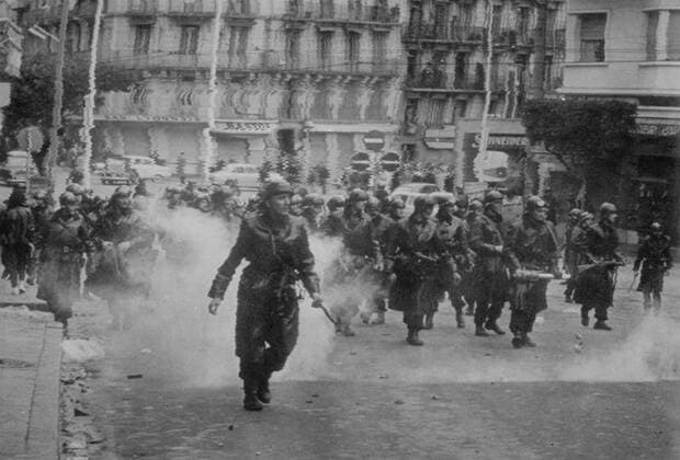 Troops armed with rifles and tear gas guns advance down an Algerian street against rioting demonstrators , Algiers , Algeria . Screaming crowds chanting Keep Algeria French went on the rampage in protest at French President de Gaulle s offer of self determination for the country . 25 January 1960 UnitedArchives00121454 