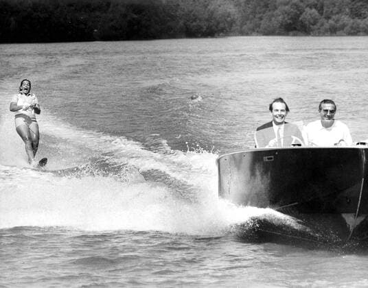 Dr. Christian Barnard takes the wheel of a speedboat accompanied by British coach, David Nations as Dr. Barnard s daughter, Deidre skims over the surface of Ruislip Lido in Middlesex as she prepares for the Wills Water Ski International. Deidre is the South African Water Ski Champion at age 18. 11th June 1968 UnitedArchives00506292 