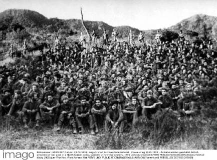 Korea-Krieg 1950-1953 - Aufnahmedaten geschätzt British prisoners of war pose in a North Korean camp, guarded by Chinese soldiers. 1951 UnitedArchives00579695 
