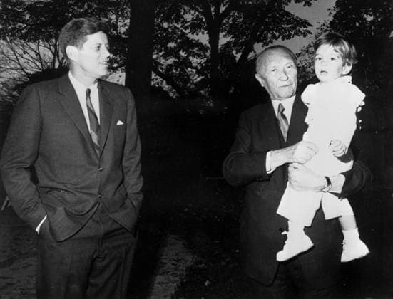 West German Chancellor Konrad Adenauer (right) holds young John Kennedy Jr as he and US President John Kennedy (left) relax in the grounds of the White House after talks . 16th November 1962 UnitedArchives00786973 
