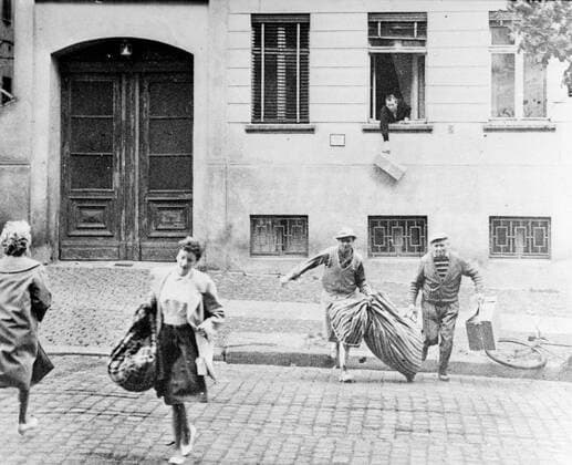 Berlin: Flashback to August 20th 1961 The picture shows the escape of an entire family just a week after the Berlin Wall was first built. In the back ground a man drops a parcel from a window of a house in Bernauer Strass which now marks the borderline. The pavement is west Berlin.. The flats in there houses were evacuated by communist on August 13th, But during the early days of the wall Bernauer Strasse was the easiest escape route, until East German sealed all doors and windows with bricks. 12 July 1969 UnitedArchives00935150 
