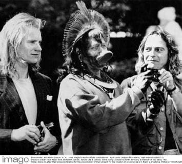 April 1989: Belgian film-maker, Jean-Pierre Dutilleux (r) shows to Indian chief Raoni from Amazonia, center, how to use a camera, whilst Sting (Gordon Sumner, formerly a member of pop band, The Police) looks on, after their press conference for the presentation of their project for the creation of a natural park in Brazil s Amazonia.  UnitedArchives00956724