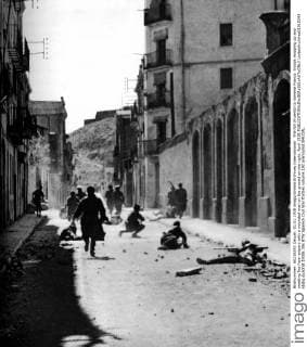 The fall of Lerida to General Franco: troops mopping up and meeting fire from snipers with a wounded man on the ground on the right. April 1938  UnitedArchives01015343