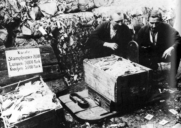 Illustration from the book GERMANY 1918-1933 Revolution counter-revolution and the rise of Hitler by Simon Taylor - Page 52 - At the height of the hyper-inflation paper currency was packed into boxes and sold as waste paper. According to the prices on the board, such money was more valuable than bones, but not as valuable as old rags! - Â  UnitedArchives01024617