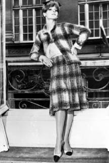 IMAGO ICONS: Coco Chanel Autumn Winter season from Coco Chanel . Chanel s winter suits featured many vivid colour combinations . This model shows her new pelated skirt topped by a slender straight jacket is in a blanket plaid in a vivid salmon and green combination , worn with a pink silk blouse . 29th July 1964  UnitedArchives01230264