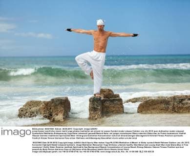 erwachsener sportlicher mann macht yoga pilates meditation am strand im wasser