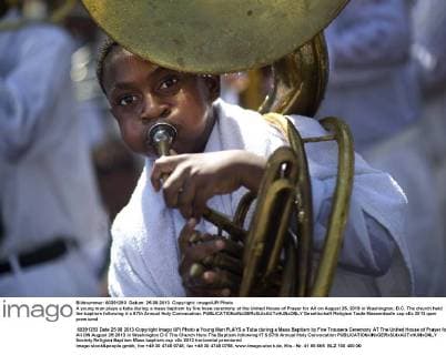 A young man plays a tuba during a mass baptism by fire hose ceremony at the United House of Prayer for All People on August 25, 2013 in Washington, D.C. The church held the baptism following it s 87th Annual Holy Convocation.  WAP20130825302