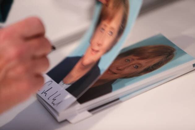 (130825) -- BERLIN, Aug. 25, 2013 (Xinhua) -- German Chancellor Angela Merkel signs her pictures during the German government s open day at the German Chancellery in Berlin, Germany, on Aug. 25, 2013. German government opened its door to the public this weekend, inviting citizens to visit several ministries and government offices in Berlin.(Xinhua Zhang Fan) GERMANY-BERLIN-POLITICS-MERKEL-OPEN DAY 
