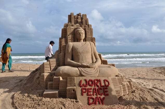 (130921) -- BHUBANESWAR, Sept. 21, 2013 (Xinhua) -- Visitors walk past a sand sculpture created by sand artist Manas Sahoo for the World Peace Day on the Bay of Bengal s sea beach in Puri, 65 km away from the eastern Indian state Orissa s capital city Bhubaneswar, India, on Sept. 21, 2013.(Xinhua Stringer) (syq) INDIA-BHUBANESWAR-WORLD PEACE DAY-SAND SCULPTURE 