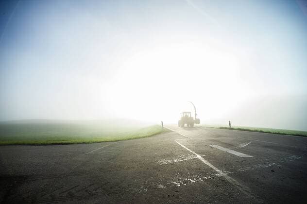 ein Traktor auf einer Landstrasse an einem Herbstmorgen mit Nebel bei Leutkirch Willerazhofen Traktor im Morgennebel