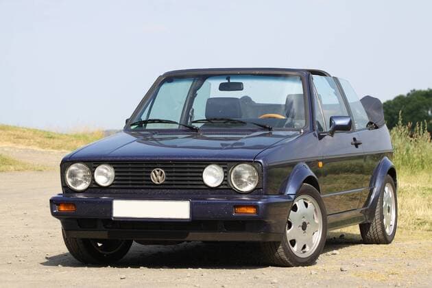 VW Golf 1 Cabriolet Quartett (Baujahr 1993, 98 PS, Farbe: Inkablau Metallic, Youngtimer) mit geöffnetem Verdeck im Sommer.