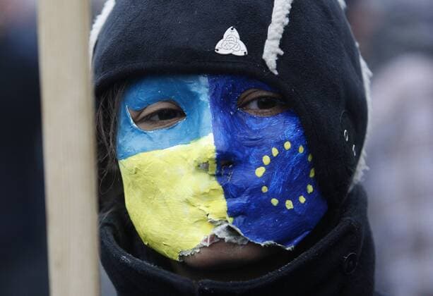 ITAR-TASS: KIEV, UKRAINE. NOVEMBER 24, 2013. Demonstrator wears a facemask painted in EU and Ukrainian national colours during a mass rally called For European Ukraine in central Kyiv. Demonstrators are protesting against the government s decision to delay an association deal with the EU.  Highlight kurios RE131421