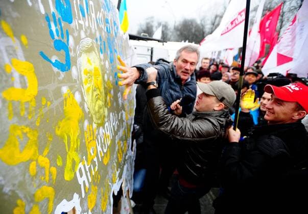 ITAR-TASS: KIEV, UKRAINE. NOVEMBER 24, 2013. Demonstrators smear a portrait of president Viktor Yanukovich during a mass rally called For European Ukraine in central Kyiv. Demonstrators are protesting against the government s decision to delay an association deal with the EU.  RE1313F3