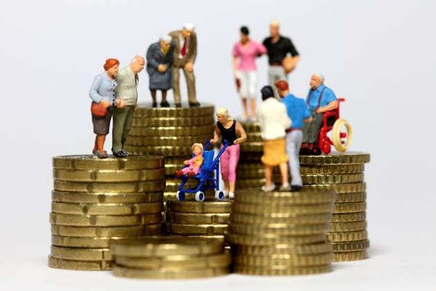 Miniatur Figuren aller Altersgruppen stehen auf Muenzstapeln