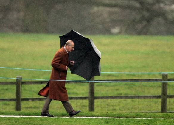 26.01.2014 Prince Philip, Duke of Edinburgh, battles with his umbrella in the rain attending St. Mary Magdalene Church for Sunday morning service in Sandringham. 