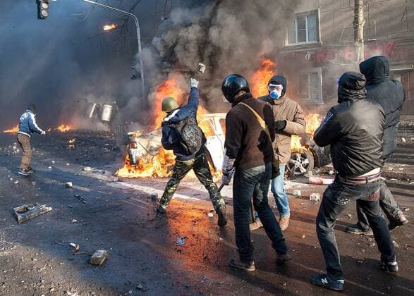 ITAR-TASS: KIEV, UKRAINE. FEBRUARY 18, 2014. Anti-government protesters throw stones at a burning car in central Kiev.  RE13A08E