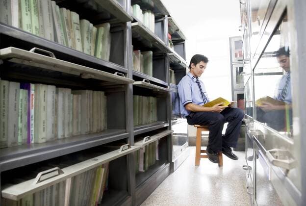 Boy reading a book in a school library 