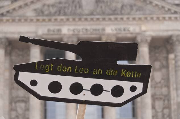 Protest gegen Rüstungsexporte aus Deutschland vor dem Reichstagsgebäude, dem Sitz des Deutschen Bundestages, im Regierungsviertel in Berlin-Tiergarten. Viele Demonstranten tragen Schilder mit einem Panzer aus Pappe auf dem Steht: Legt den Leo an die Kette . Protest gegen Rüstungsexporte