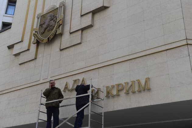 (140318) -- SIMFEROPOL, March 18, 2014 (Xinhua) -- Workers dismantle the Ukrainian signs on Crimean Parliament building in Simferopol, the Republic of Crimea, March 18, 2014. Russian President Vladimir Putin and leaders of Crimea signed a treaty on Tuesday accepting the Republic of Crimea and the city of Sevastopol as part of the Russian territory. (Xinhua Sadat) (srb) CRIMEA-SIMFEROPOL-RUSSIA-TREATY 