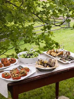A buffet table set up in a garden for al al fresco meal. Salads and prepared food dishes. 