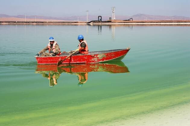 Two workers with security helmet on a boat, rowing through salt pools in the Salar de Atacama, Chile, taking samples of the brine. Oliver Llaneza Hesse  ZB5441_241438_0165